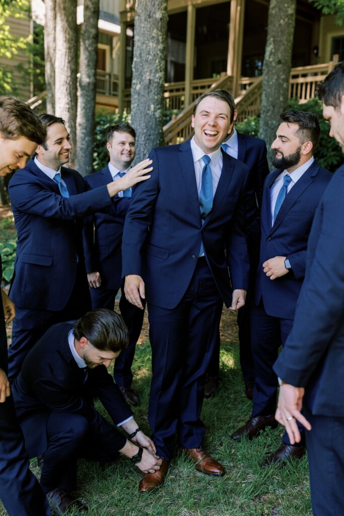 Groom surrounded by groomsmen in navy suits during outdoor wedding celebration at Meghan Rose Photography.