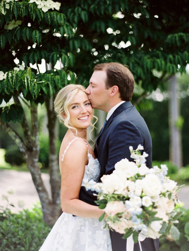 Elegant wedding portrait of a bride and groom outdoors, celebrating love on their special day with lush greenery in the background.