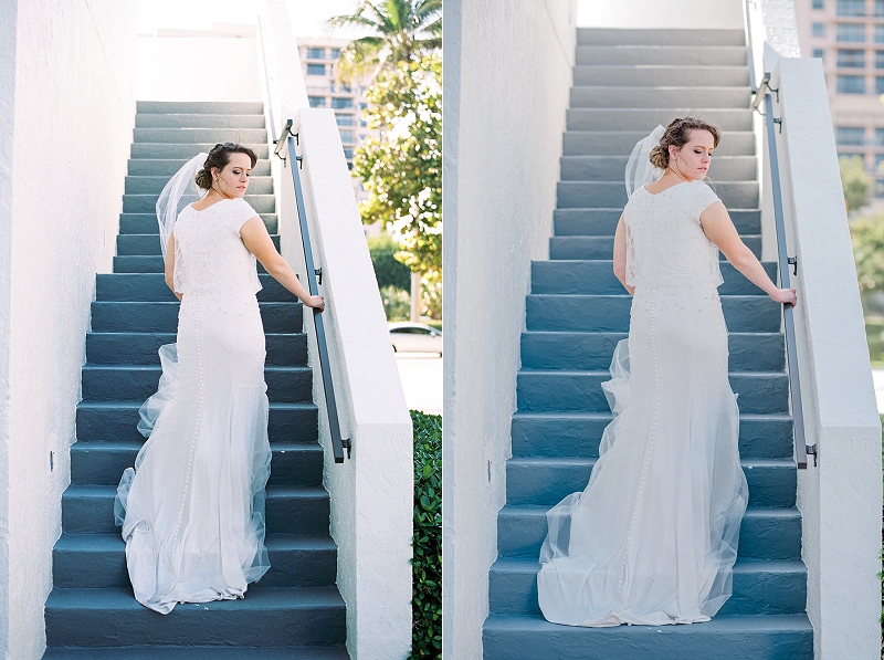 bride with cathedral veil stands on blue stairwell