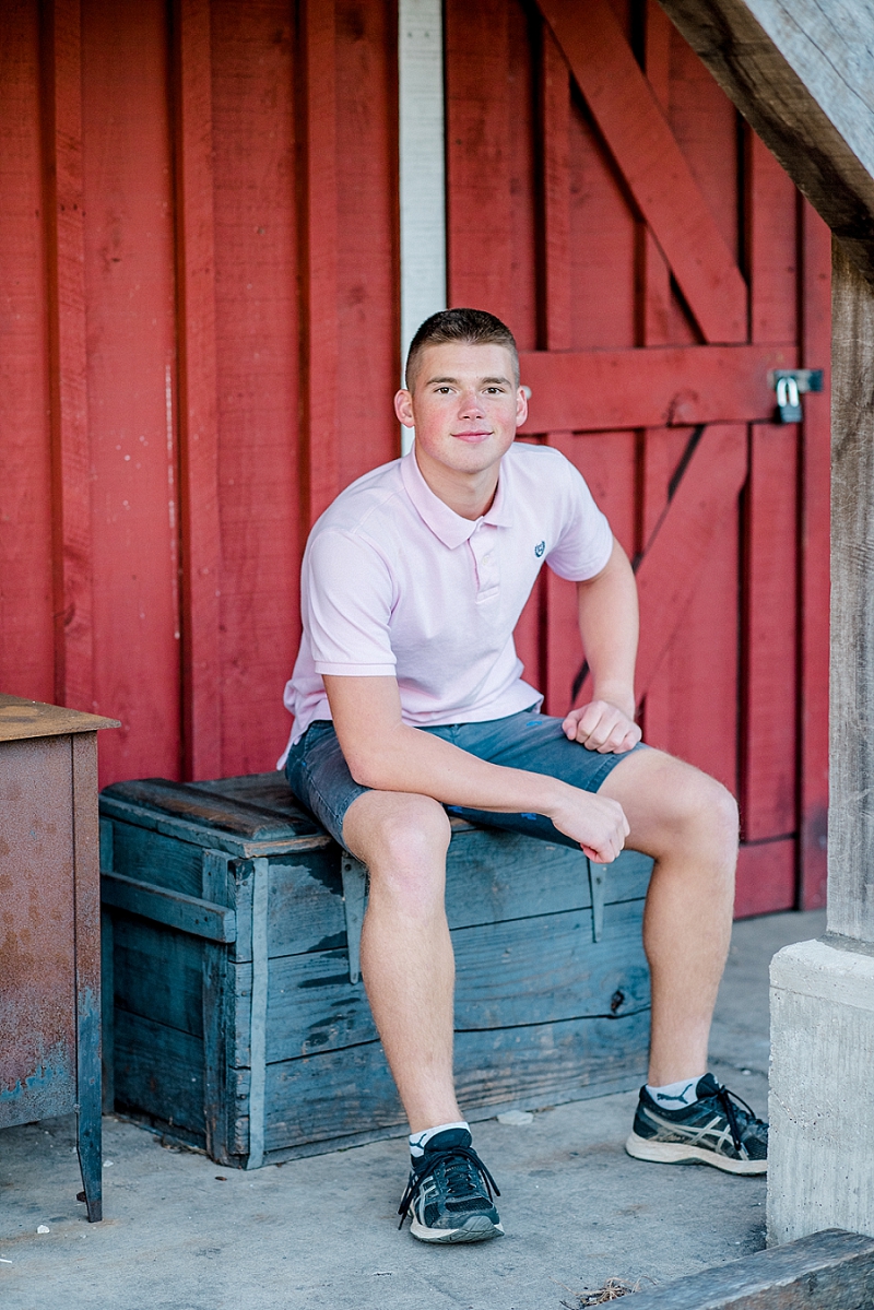 senior boy in front of red barn